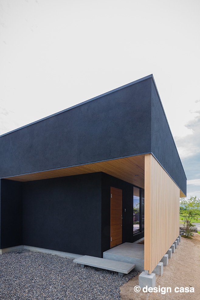 土間コンクリートと木質建材のエントランス、モダンなダークブルーの外壁
