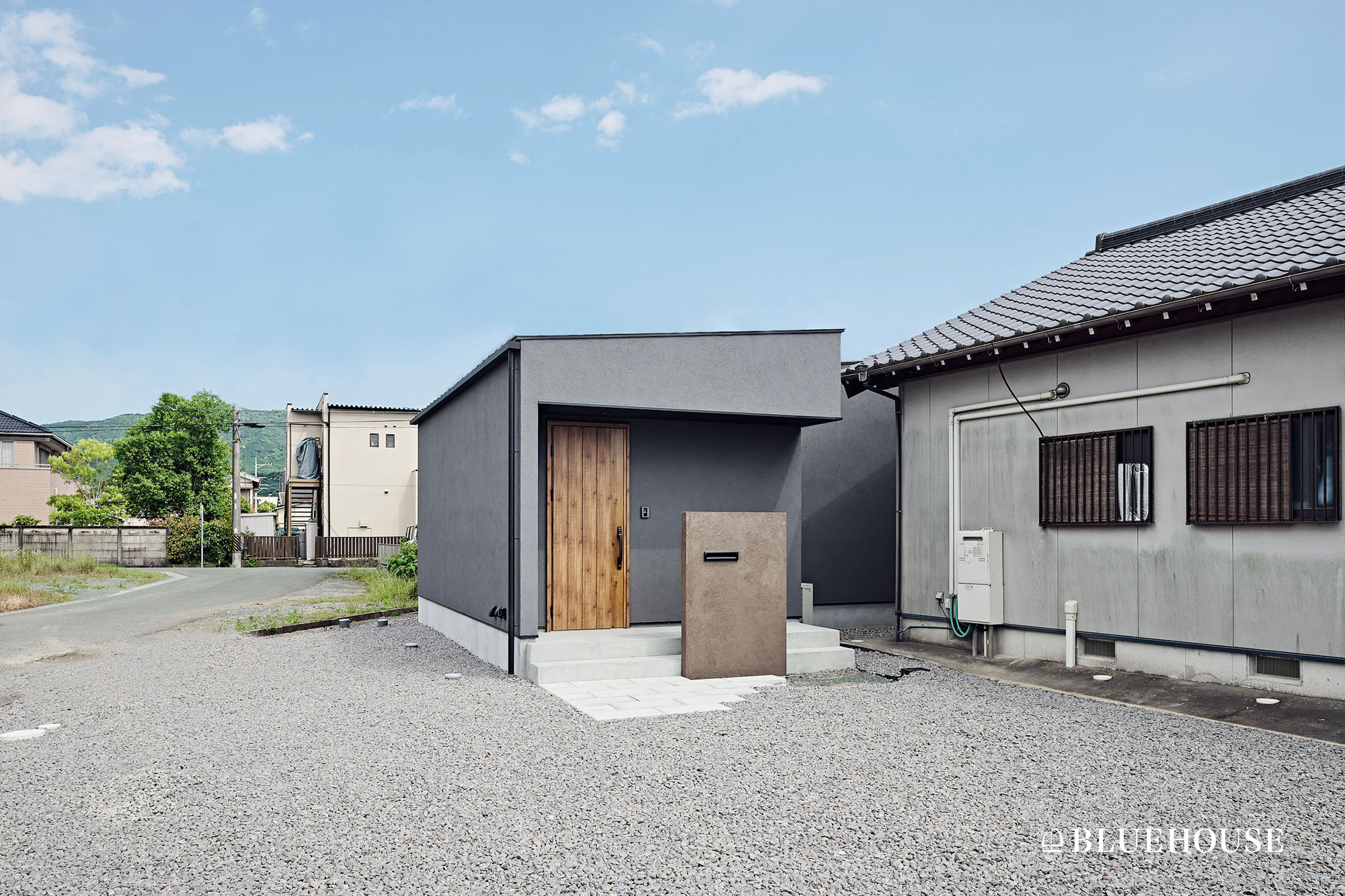 グレーの外壁と木製玄関ドアが特徴的な、平屋住宅の外観